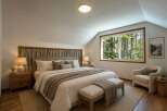 Experience serene living in this charming bedroom, featuring a plush king-size bed adorned with cozy linens and decorative pillows.