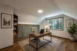 Discover your ideal home office in this charming attic space, featuring a large window with serene forest views.