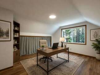 Discover your ideal home office in this charming attic space, featuring a large window with serene forest views.