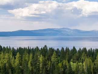 Experience breathtaking lake and mountain views from this stunning property, nestled amidst a lush evergreen forest.
