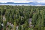Nestled within a dense pine forest, this property offers a serene retreat with stunning views of a distant lake and mountains.