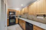 This charming kitchen features light wood cabinetry and a sleek black range with a matching microwave above.