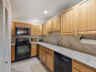 This charming kitchen features light wood cabinetry and a sleek black range with a matching microwave above.