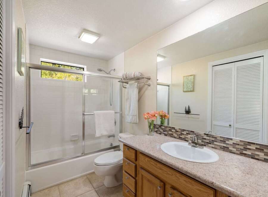 This bright and airy bathroom features a spacious vanity with a granite countertop and ample storage.