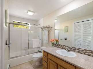 This bright and airy bathroom features a spacious vanity with a granite countertop and ample storage.