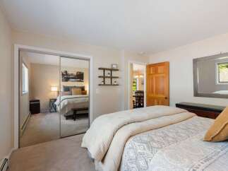 This inviting bedroom features a spacious layout with a large mirrored closet, offering ample storage and reflecting natural light.