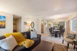 Experience comfortable living in this inviting open-concept space, featuring a spacious living area with a plush leather sofa and a cozy yellow throw, perfect for relaxation.