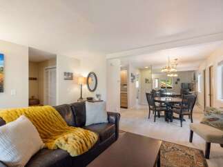 Experience comfortable living in this inviting open-concept space, featuring a spacious living area with a plush leather sofa and a cozy yellow throw, perfect for relaxation.