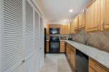 Discover this charming kitchen featuring light wood cabinetry and a sleek black appliance suite, including a microwave and oven.