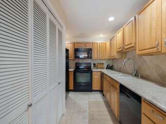 Discover this charming kitchen featuring light wood cabinetry and a sleek black appliance suite, including a microwave and oven.