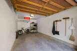 This spacious garage offers ample storage solutions, including overhead shelving and a multi-tiered rack, perfect for organizing tools and equipment.
