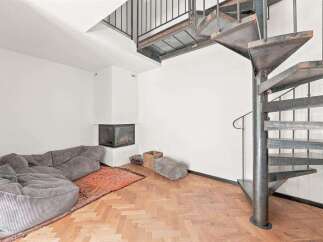 Experience modern living with this spacious loft featuring a cozy sectional sofa and a striking spiral staircase.