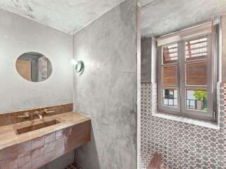 Discover a unique bathroom design featuring a floating concrete vanity with a built-in sink and brass fixtures.