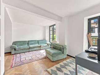 Experience stylish living in this apartment featuring a plush, sage green sectional sofa complemented by a vintage-inspired rug.