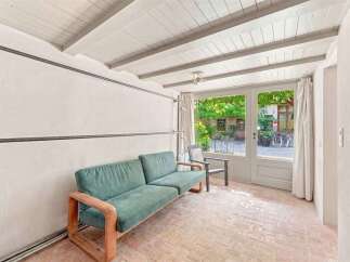 Step into this charming sunroom, featuring a comfortable teal sofa and a rustic wooden frame, perfect for relaxing.