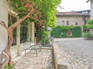 Step into a charming courtyard featuring a rustic stone building adorned with lush greenery.
