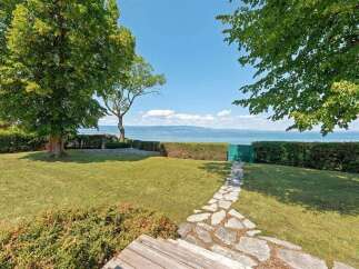 Enjoy breathtaking lake views from this stunning property, featuring a meticulously manicured lawn and a charming stone pathway leading to the water's edge.