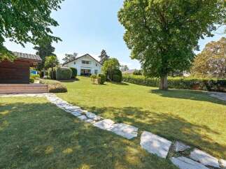 Discover this stunning property featuring a beautifully manicured lawn and a charming stone pathway leading to a modern white house.