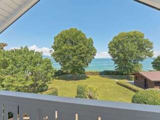 Enjoy breathtaking lake views from this stunning property, featuring a lush green lawn perfect for outdoor activities.