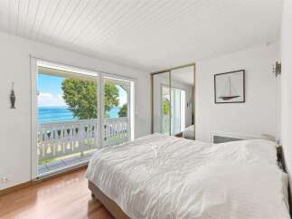 Experience breathtaking ocean views from this serene bedroom, featuring a spacious bed and direct access to a private balcony.