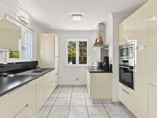 This modern kitchen features sleek, cream-colored cabinetry and a dark countertop, offering a sophisticated look.