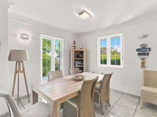 Bright and airy dining room featuring a light wood table surrounded by wicker chairs, perfect for family meals.