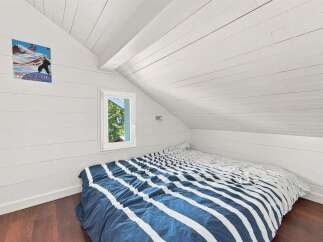 Discover this charming attic bedroom, featuring a cozy bed with a striking blue and white striped comforter.