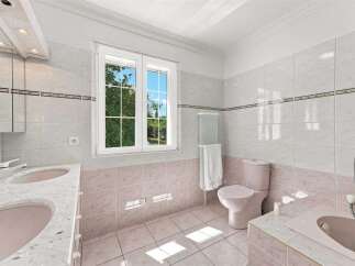 This charming bathroom features a double vanity with pink sinks and a marble countertop, perfect for busy mornings.