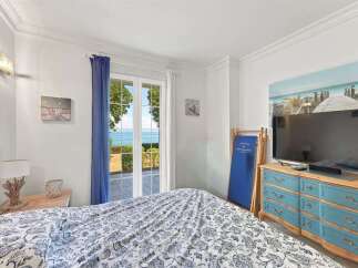 Experience coastal living in this charming bedroom featuring a comfortable bed with a beautiful blue and white patterned comforter.