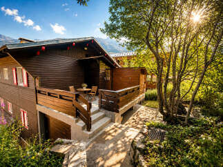 Experience the charm of this rustic wooden chalet, nestled amidst lush greenery and bathed in the warm glow of the sun.