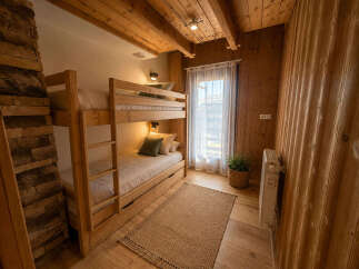 Experience cozy living in this charming room featuring a sturdy wooden bunk bed, perfect for families or guests.