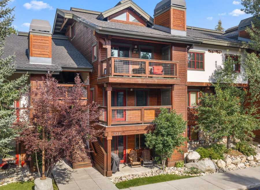 Experience luxury mountain living in this stunning wood-accented condo, featuring multiple balconies with scenic views and a welcoming patio area.