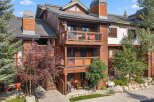Experience luxury mountain living in this stunning wood-accented condo, featuring multiple balconies with scenic views and a welcoming patio area.
