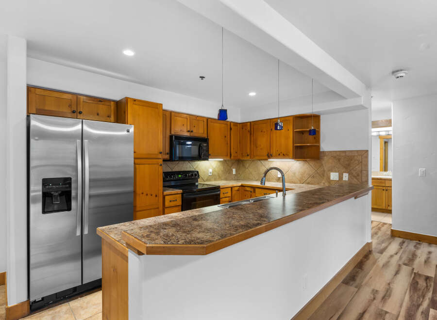 Discover this charming kitchen featuring warm wooden cabinetry and a sleek stainless steel refrigerator.