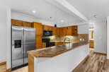 Discover this charming kitchen featuring warm wooden cabinetry and a sleek stainless steel refrigerator.