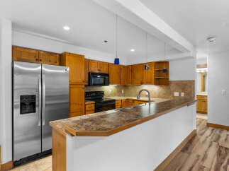 Discover this charming kitchen featuring warm wooden cabinetry and a sleek stainless steel refrigerator.