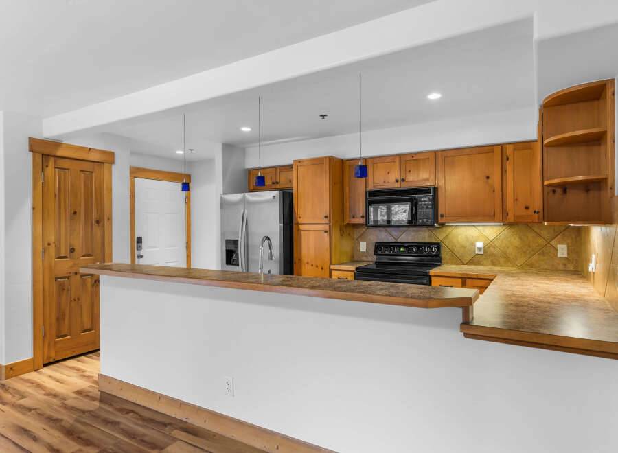 This spacious kitchen features warm wooden cabinetry and a convenient breakfast bar, perfect for casual dining or entertaining guests.
