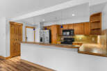 This spacious kitchen features warm wooden cabinetry and a convenient breakfast bar, perfect for casual dining or entertaining guests.