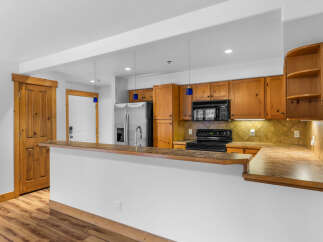 This spacious kitchen features warm wooden cabinetry and a convenient breakfast bar, perfect for casual dining or entertaining guests.