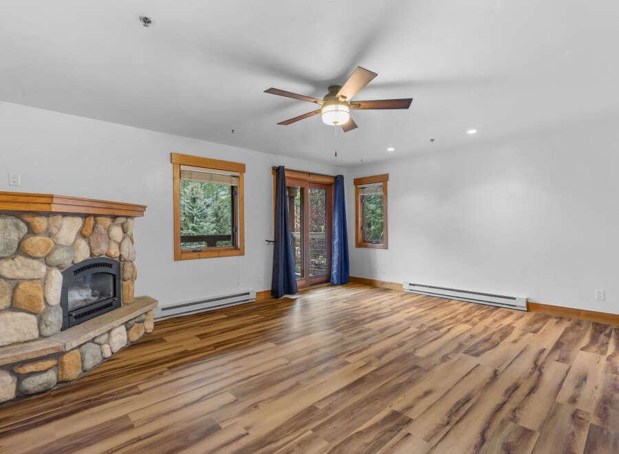 Cozy living room featuring a rustic stone fireplace and a ceiling fan for year-round comfort.