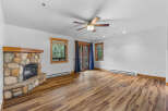Cozy living room featuring a rustic stone fireplace and a ceiling fan for year-round comfort.