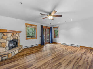 Cozy living room featuring a rustic stone fireplace and a ceiling fan for year-round comfort.