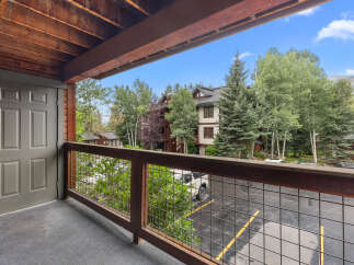 Enjoy the fresh mountain air from this charming balcony, offering a serene view of the surrounding trees and architecture.