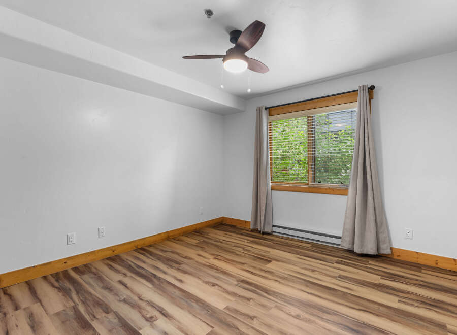 This room features a modern ceiling fan and a large window with blinds, offering ample natural light.