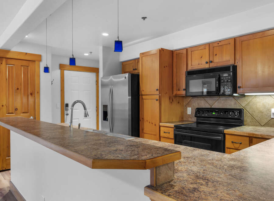 Discover this charming kitchen featuring warm wooden cabinetry and a spacious granite countertop island, perfect for meal preparation and casual dining.
