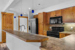 Discover this charming kitchen featuring warm wooden cabinetry and a spacious granite countertop island, perfect for meal preparation and casual dining.