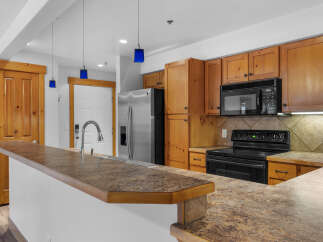 Discover this charming kitchen featuring warm wooden cabinetry and a spacious granite countertop island, perfect for meal preparation and casual dining.