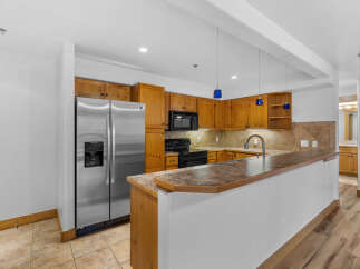 This spacious kitchen features warm wooden cabinetry and a sleek stainless steel refrigerator.