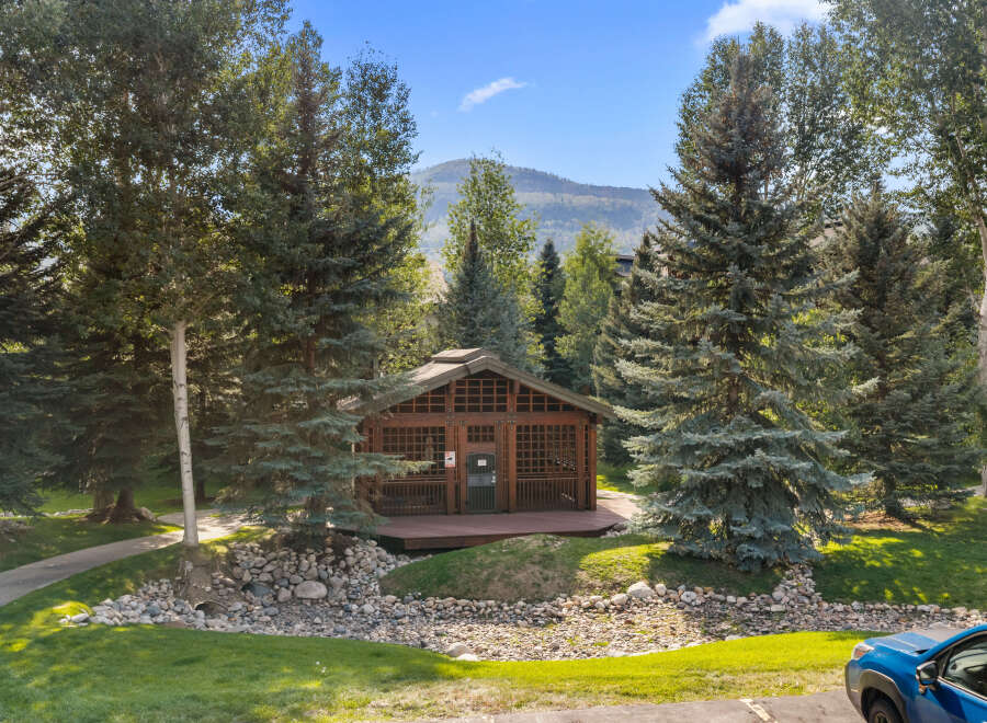 Nestled amidst mature trees and a serene mountain backdrop, this charming wooden cabin offers a unique retreat.