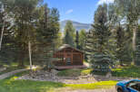 Nestled amidst mature trees and a serene mountain backdrop, this charming wooden cabin offers a unique retreat.
